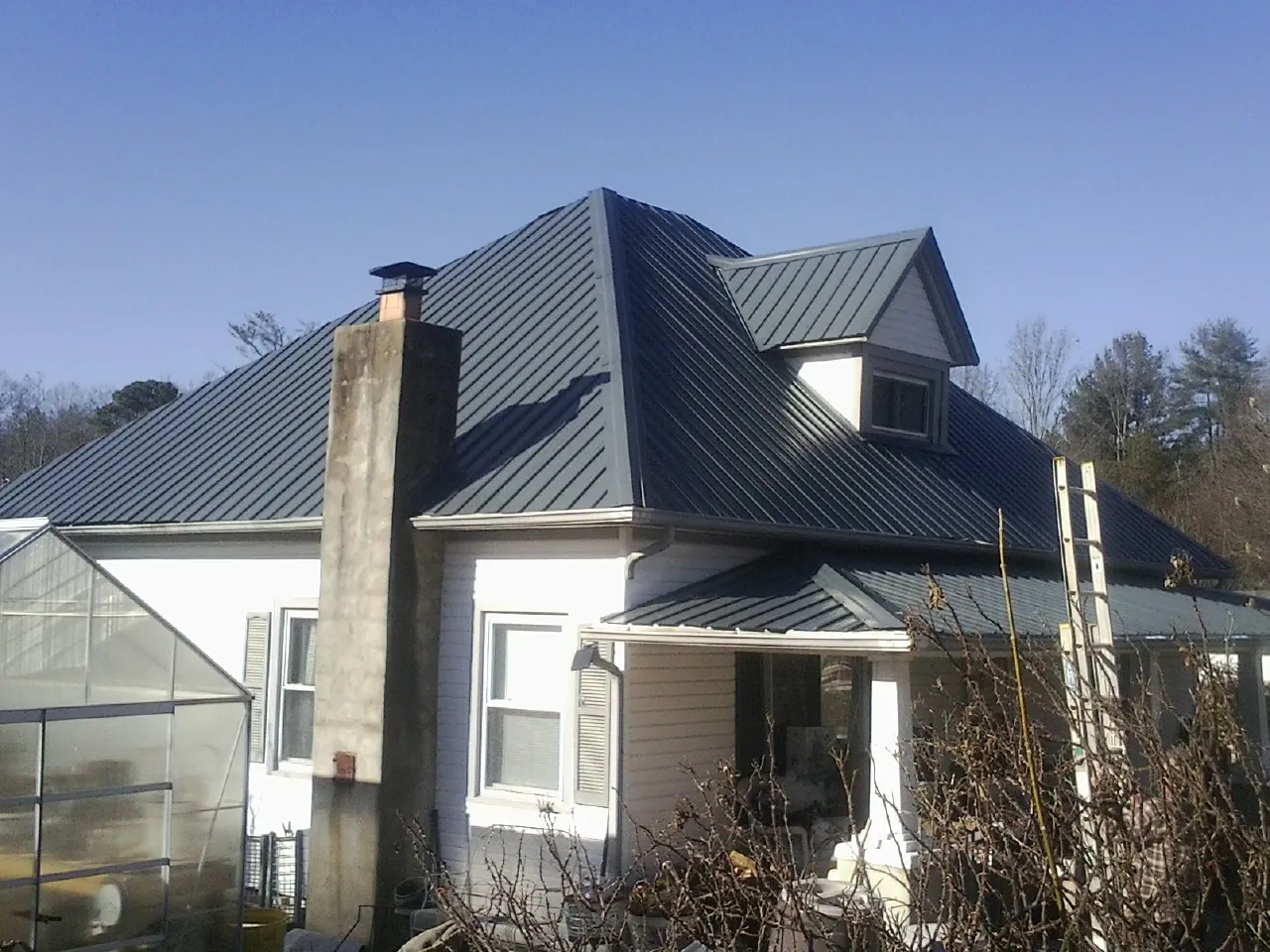 Dark blue standing seam metal roof on a white farmhouse with dormer — Slate & Tile Roof Repair by Roofing Brothers in Hardwick
