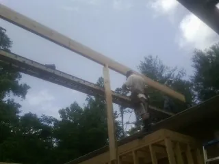 Carpenter setting a ridge beam over a new addition frame — Ice Dam Removal by Roofing Brothers in Hardwick